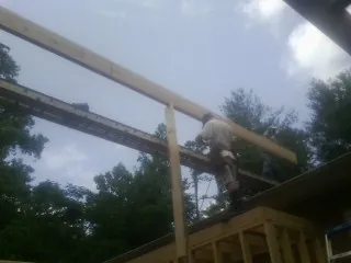 Carpenter setting a ridge beam over a new addition frame — Ice Dam Removal by Roofing Brothers in Nortonville