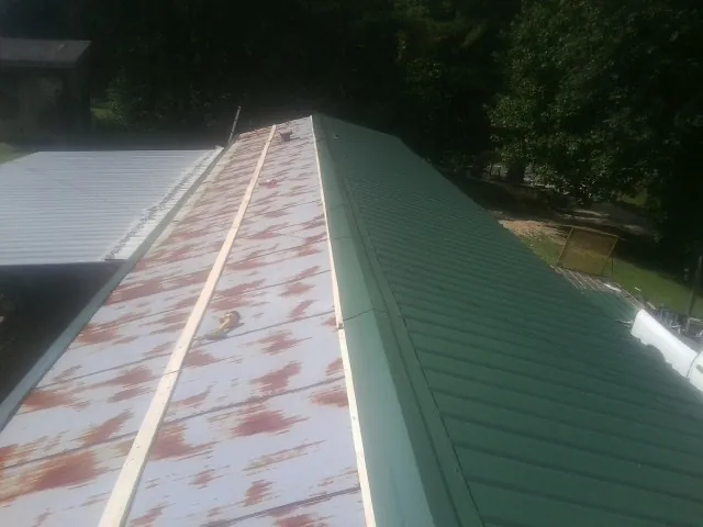 Old rusted panels beside newly installed green metal roofing — Wind Damage Roof Repair by Roofing Brothers in Nortonville