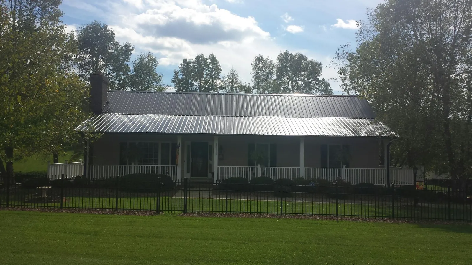 Gray metal roof on a brick ranch with a full width front porch — Gutter Guard Installation work by our crew in Nortonville